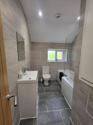 a bathroom with a sink and a toilet and a tub at Parkgate Charming Cottage in Chelsfield