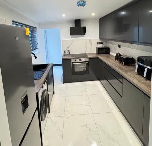eine Küche mit schwarzen Schränken und einer Waschmaschine und einem Trockner in der Unterkunft Your Home Away, Luxury House in Swansea