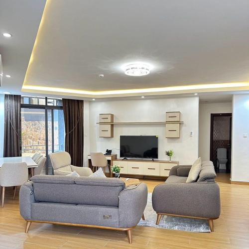 a living room with two couches and a flat screen tv at Cascadia Apartments Kigali in Kigali