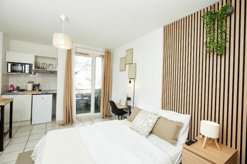 Cet appartement comprend une chambre avec un lit blanc et une cuisine. dans l'établissement Le Chic Urbain - Hôpitaux Facultés - Chateau d'Ô - Free Parking, à Montpellier
