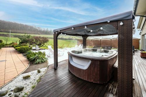 a hot tub on a deck with an umbrella at Dosłońce Resort Wellness & Farm in Racławice