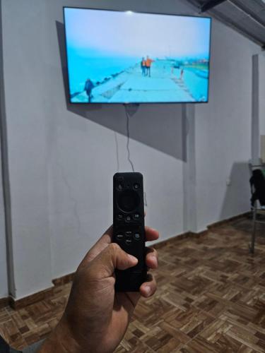 a person holding a remote control in front of a television at Minidepartamento Centrico Amoblado in Piura