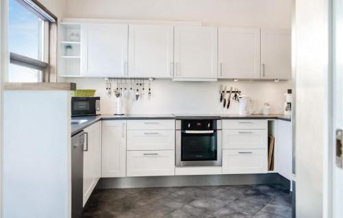 a white kitchen with white cabinets and appliances at Holiday Home Hellesvej Vestervig Denm in Vestervig