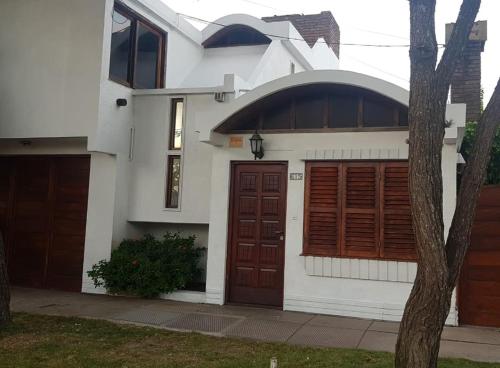 a white house with brown doors and a tree at Duplex la 70 in San Clemente del Tuyú