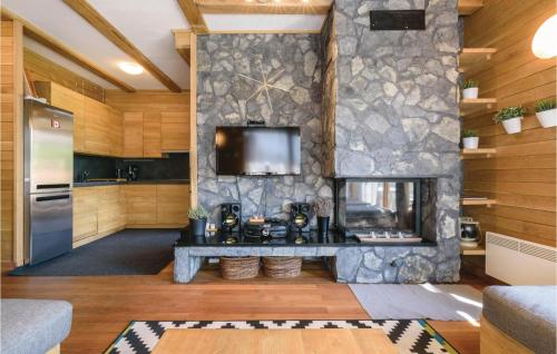 a living room with a stone fireplace and a tv at Beautiful Home In Gornji Zvecaj in Gornji Zvečaj