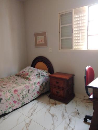 a bedroom with a bed and a dresser and a window at Casa Amarela-Quartos in Uberlândia