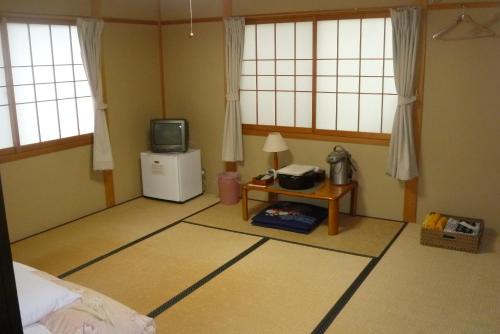a room with a bed and a tv and windows at Ryokan Shimizu in Kyoto