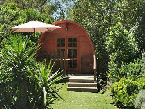 une petite cabane en bois avec un parasol dans un jardin dans l'établissement Ma cabane au fond du jardin, à Porto-Vecchio