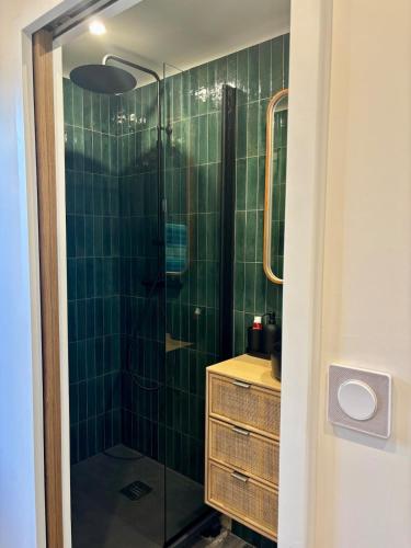 La salle de bains carrelée de couleur verte est pourvue d'une douche en verre. dans l'établissement Sea view apartment with balcony, à Saint-Malo