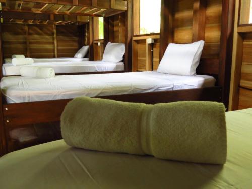 two beds in a room with towels on a table at Vocaré Finca Agroecológica in Upala