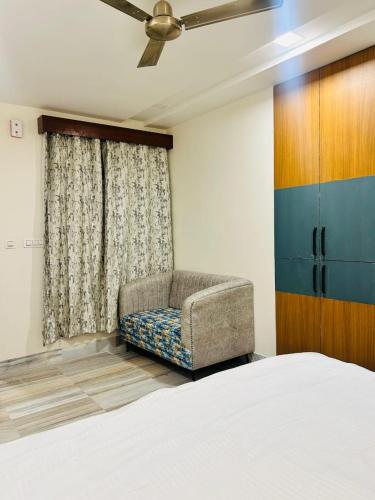 a bedroom with a bed and a chair and a window at Holiday Out Hotel in Jodhpur