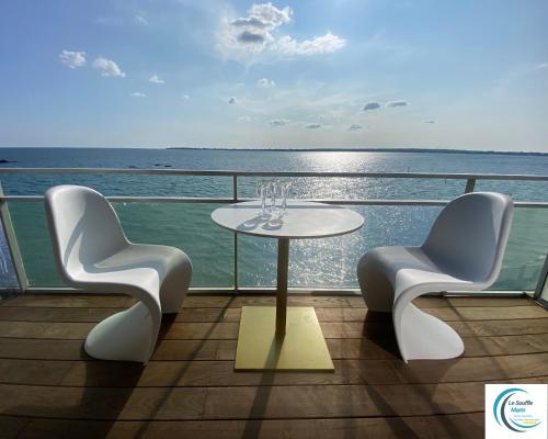 a table and two chairs on a balcony with the ocean at Le Souffle Marin CONCARNEAU - VUE MER panoramique DIRECT sur la PLAGE des Sables Blancs FIBRE Parking PRIVÉ Secure PANORAMIC SEE VIEW direct ON BEACH in Concarneau