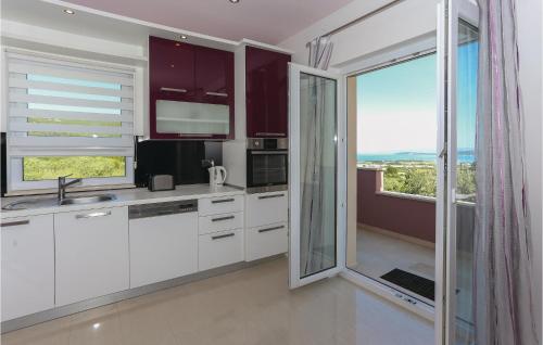 a kitchen with white cabinets and a large window at Amazing Home In Kastel Stafilic in Plano
