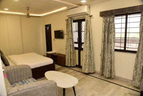 a bedroom with a bed and a chair and window at Holiday Out Hotel in Jodhpur