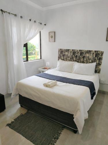 a bedroom with a large white bed with a window at Masingita Guest House in Graskop