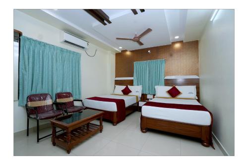 a bedroom with two beds and a table and chairs at HOTEL THANVI iNN in Guntūr
