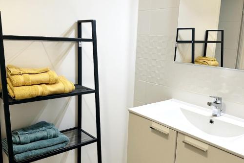 a bathroom with a sink and a shelf with towels at Studio Récent Prés d'Arènes Terrasse Wifi parking privé in Montpellier