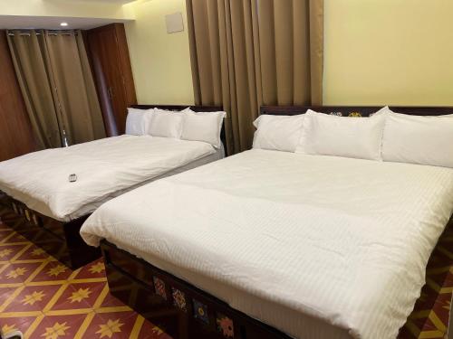 two beds in a hotel room with white sheets at Nathan STAY Srirangam - Uniquely Designed for a Memorable Stay in Tiruchchirāppalli