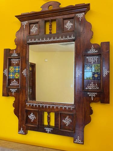 a mirror on a wall with a wooden frame at Nathan STAY Srirangam - Uniquely Designed for a Memorable Stay in Tiruchchirāppalli