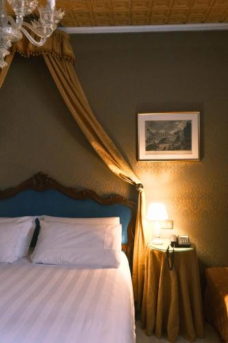 a bedroom with a bed with a blue headboard and curtains at H O T E L S A N G A L L O l in Venice