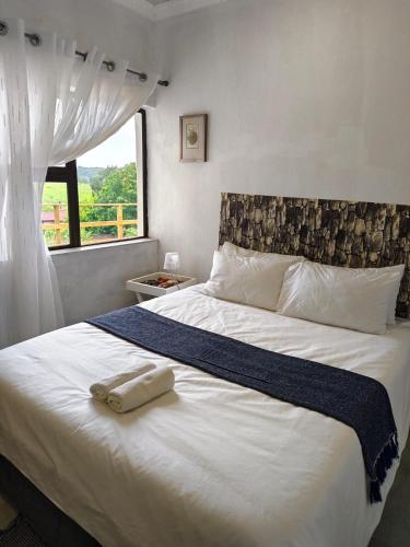 a bedroom with a large white bed with a window at Masingita Guest House in Graskop