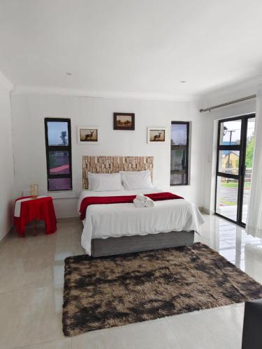a white bedroom with a large bed with a red blanket at Masingita Guest House in Graskop