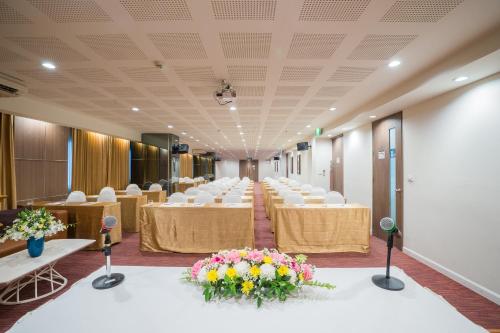 a conference room with tables and chairs and flowers at Beyond Suite in Bangkok
