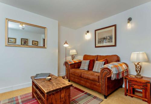a living room with a brown couch and a table at Jacobite's Retreat, 17th century cottage in the heart of Inverness in Inverness