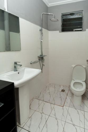 a white bathroom with a sink and a toilet at Akeva in Brazzaville