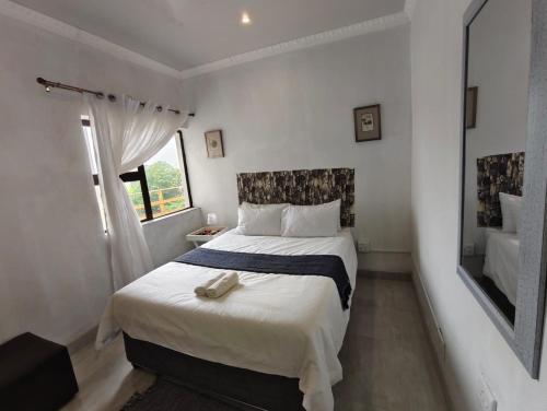 a bedroom with a large white bed with a mirror at Masingita Guest House in Graskop