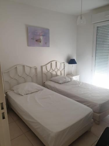 - 2 lits dans une chambre blanche avec fenêtre dans l'établissement Appartement duplex 6 personnes Cannes Grand Parc, à Cannes