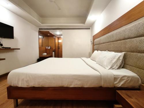 a bedroom with a large white bed and a television at The Sky Comfort, Ahmedabad in Ahmedabad