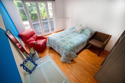 a bedroom with a bed and a chair and a window at MRE Goldsmith Polanco in Mexico City