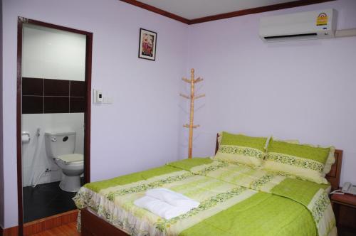 una camera con letto verde e servizi igienici di Phoonsab Hostel a Phitsanulok