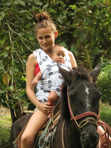 a woman holding a baby on a horse at Vocaré Finca Agroecológica in Upala