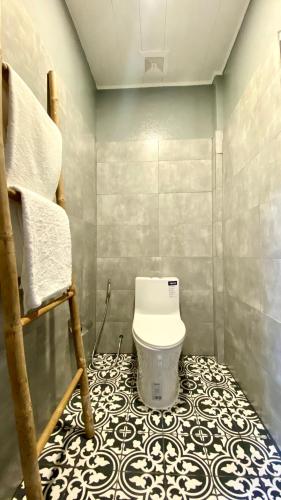 a bathroom with a toilet and a tiled floor at Cozy Paradise in Battambang
