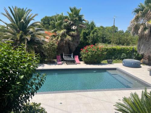 une piscine dans une cour avec des palmiers dans l'établissement Chez Isa - avec piscine chauffée et jacuzzi, à Gigean