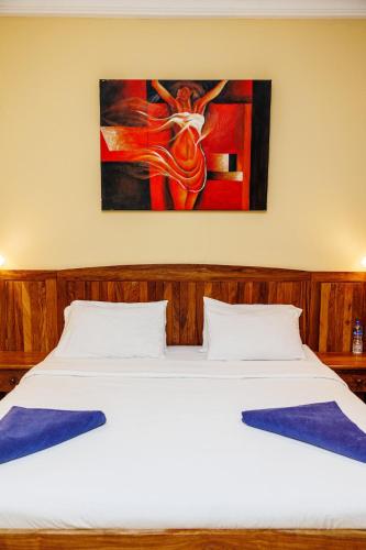 a bedroom with a bed with a painting on the wall at Senegambia Beach Hotel in Kololi