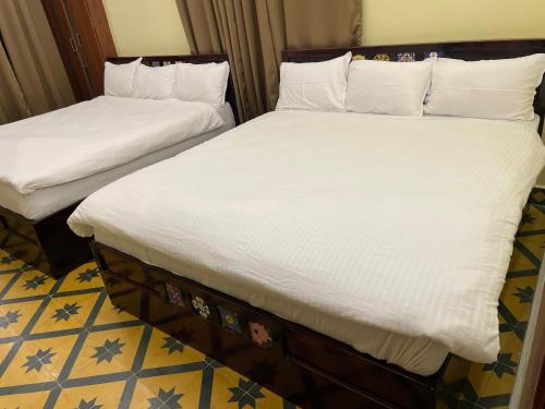 two beds with white sheets in a room at Nathan STAY Srirangam - Uniquely Designed for a Memorable Stay in Tiruchchirāppalli