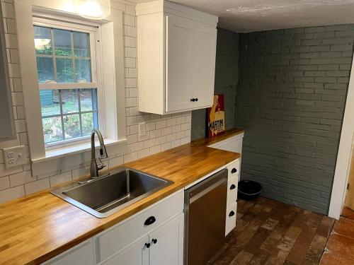 Una cocina con gabinetes blancos y un fregadero. en Cabin in the Woods, en Hillsborough
