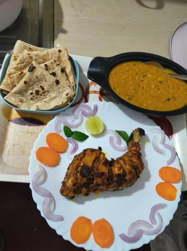 a plate with a piece of meat and a pan of food at Perch Next door in Kannur