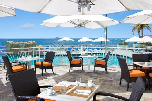 a restaurant with tables and chairs and a view of the ocean at Oyster Bay Beach Resort in Dawn Beach