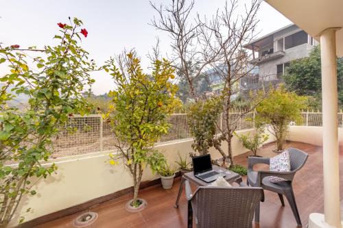 a balcony with trees and a laptop on a table at Alaya Stays Cozy Nest 2 BHK Cottage with Garden in Bhīm Tāl
