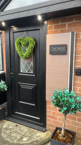 a black door with a heart shaped wreath on it at The Nest - Cosy Rooms in Harwood