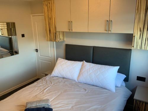 a bed with white sheets and a blue headboard at The Nest - Cosy Rooms in Harwood