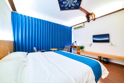 a bedroom with a bed and a blue curtain at Destination Youth Hostel in Zhangjiajie