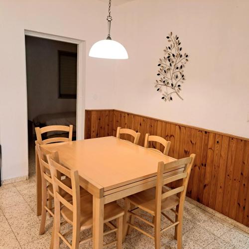a dining room with a wooden table and chairs at לטייל בחוץ להרגיש בבית in H̱efẕi Bah