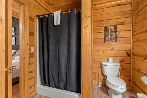a bathroom with a black shower curtain in a log cabin at NewListing 1mile Parkway, GameRoom, HotTub, BBQ, Sleeps 14, 5 Bedroom with attached Bath, PET Friendly in Pigeon Forge