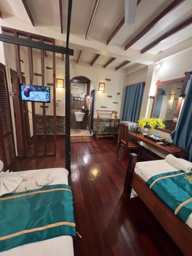 a living room with two beds and a flat screen tv at Chaluenxay Legend Hotel in Luang Prabang