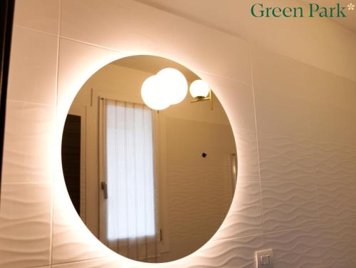a round mirror in a bathroom with a light at Green Park Rooms in San Donato Milanese
